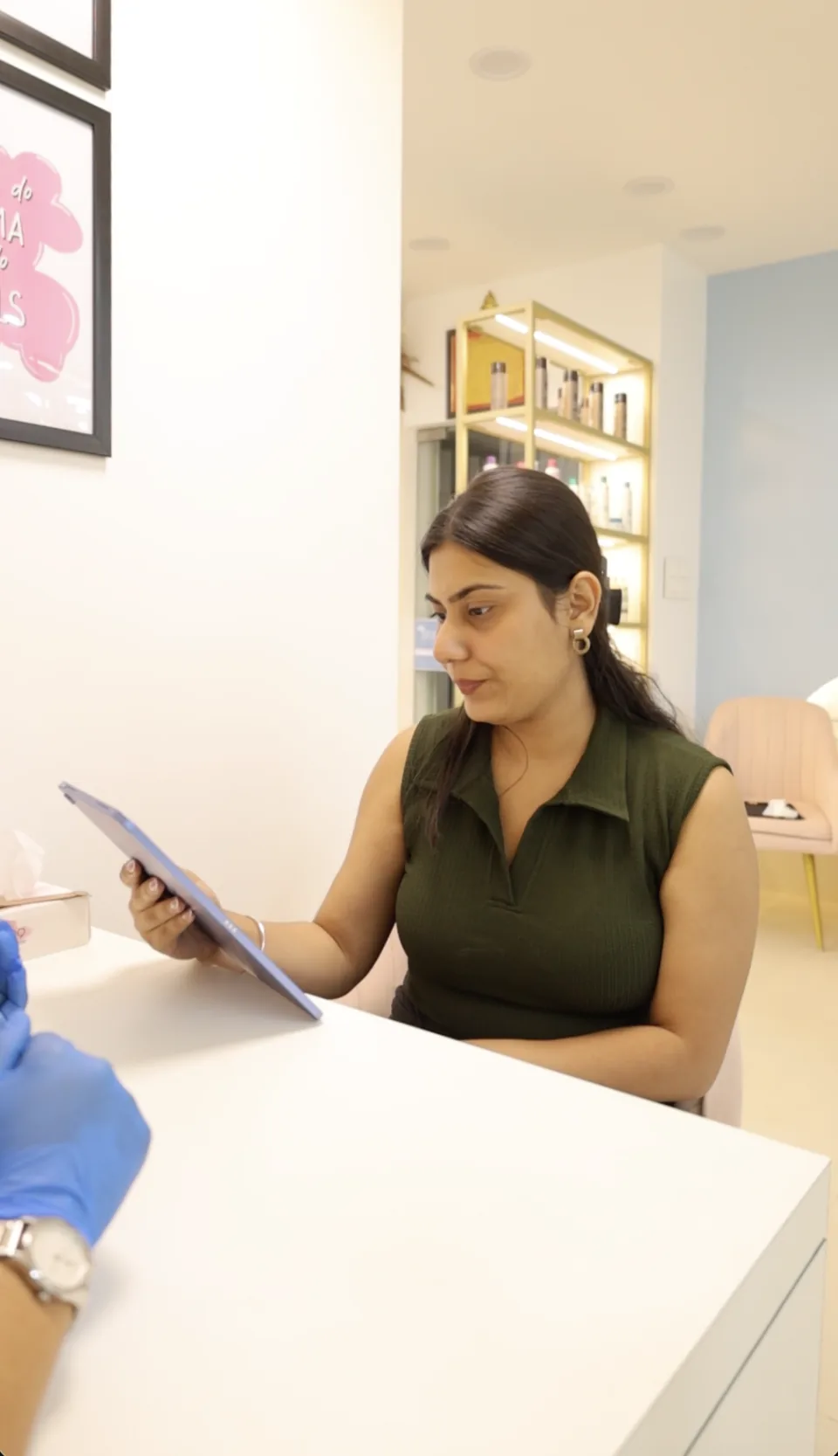A client looks at a device while discussing her nail design with the technician.