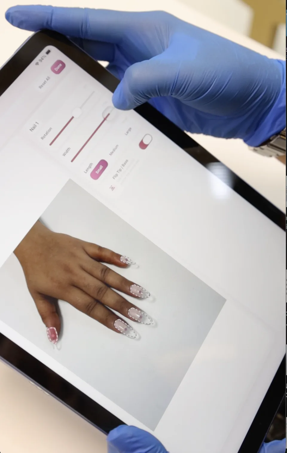 A technician uses nail extension adjustment controls on an iPad.