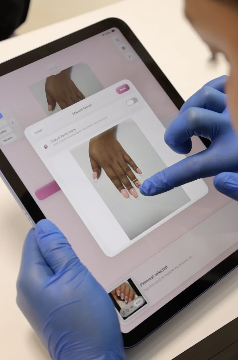 A gloved technician refines an individual nail using the iPad adjustment panel.