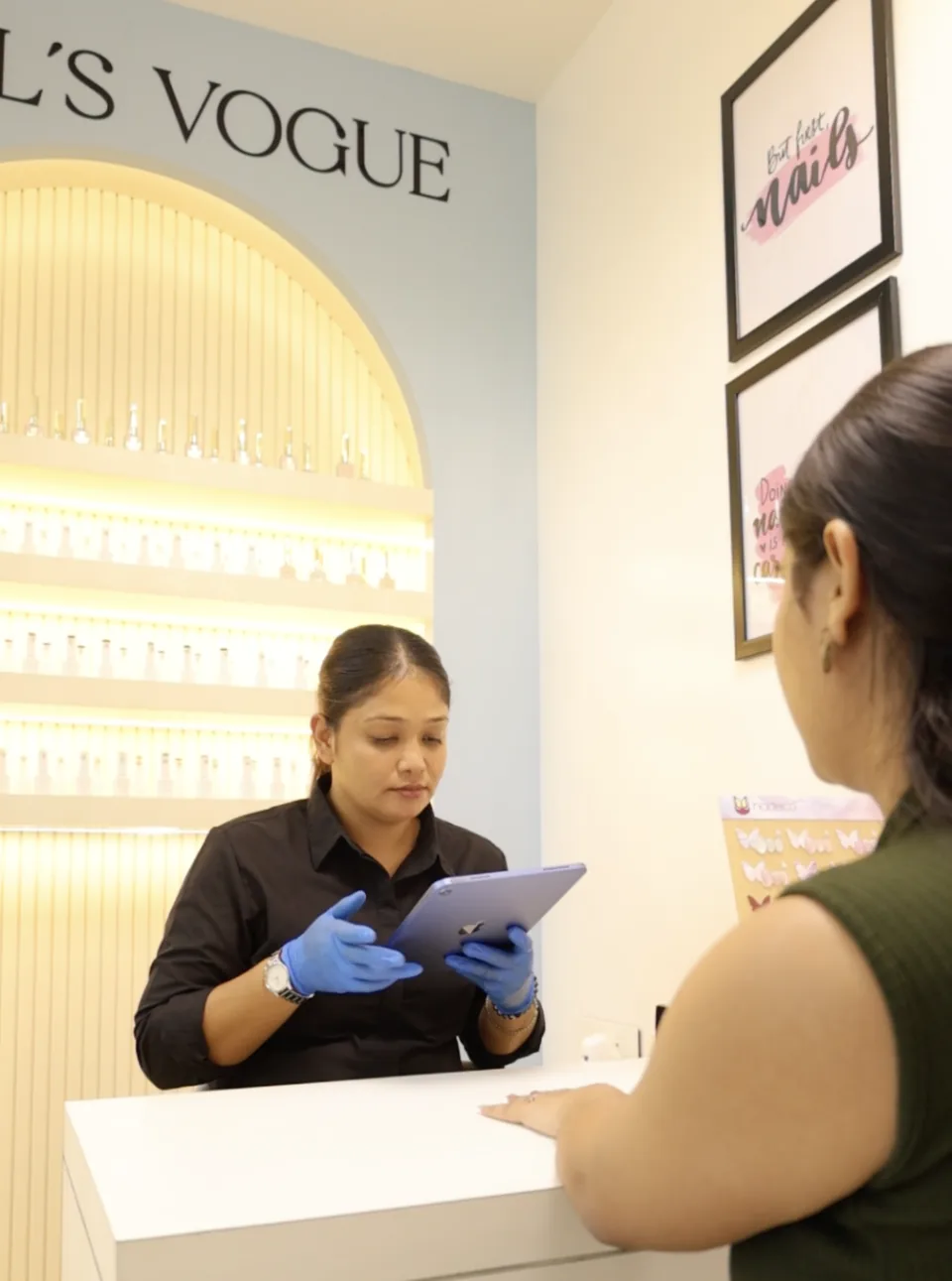 A nail technician uses an iPad while consulting with a client at Studio99’s Nails Vogue nail station.