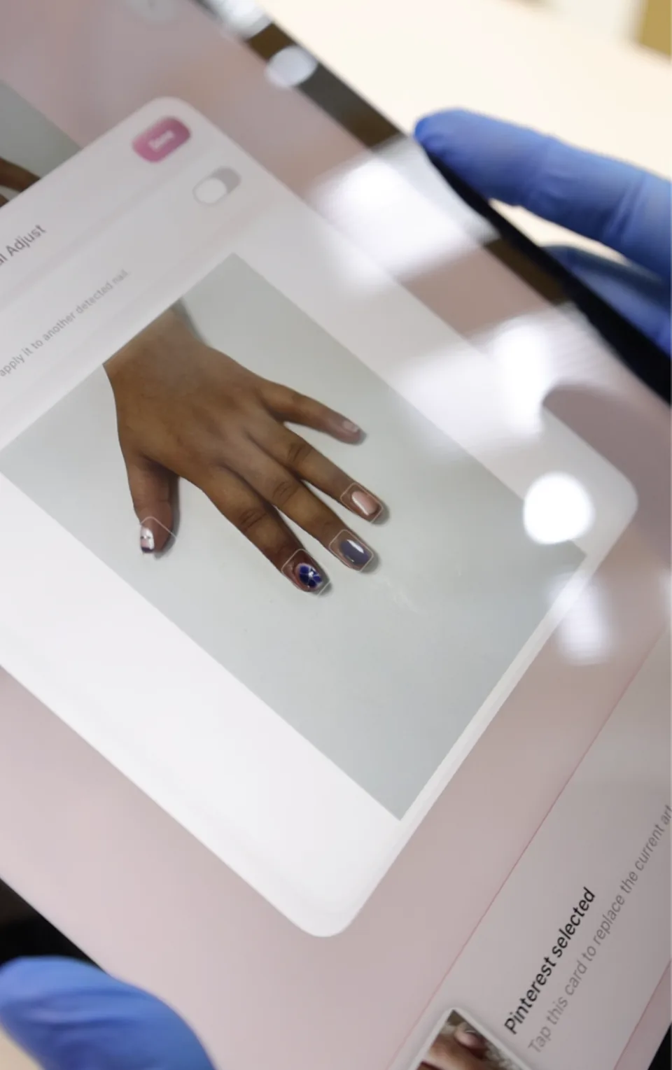 A close-up of virtual nail art applied to the hand preview on an iPad.