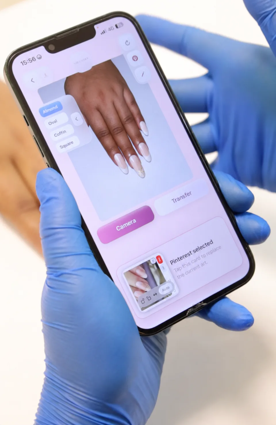 A phone at Studio99 displays a French-tip nail design transferred from reference artwork onto the client’s hand, with nail shape options visible.