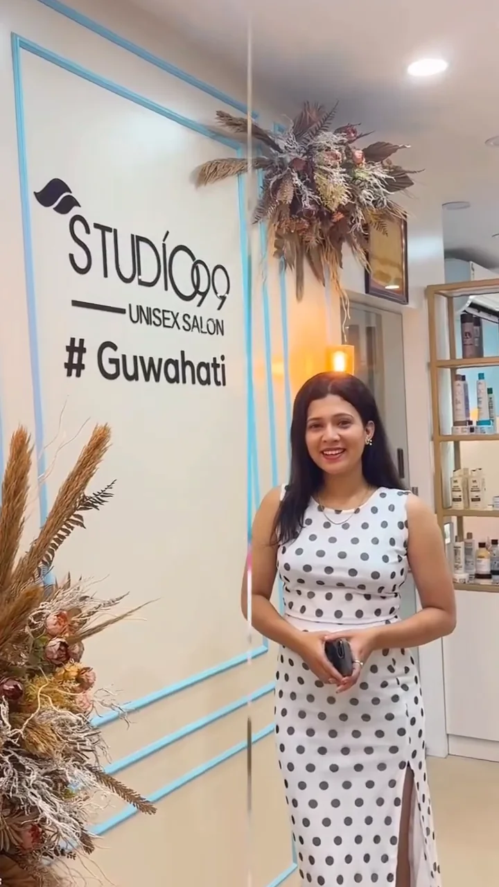A visitor stands beside the Studio99 Guwahati sign inside the salon.